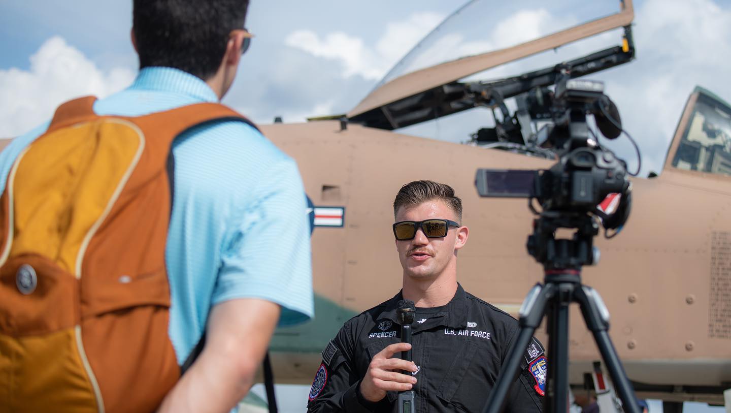 Pilot speaking to interviewer in front of plane