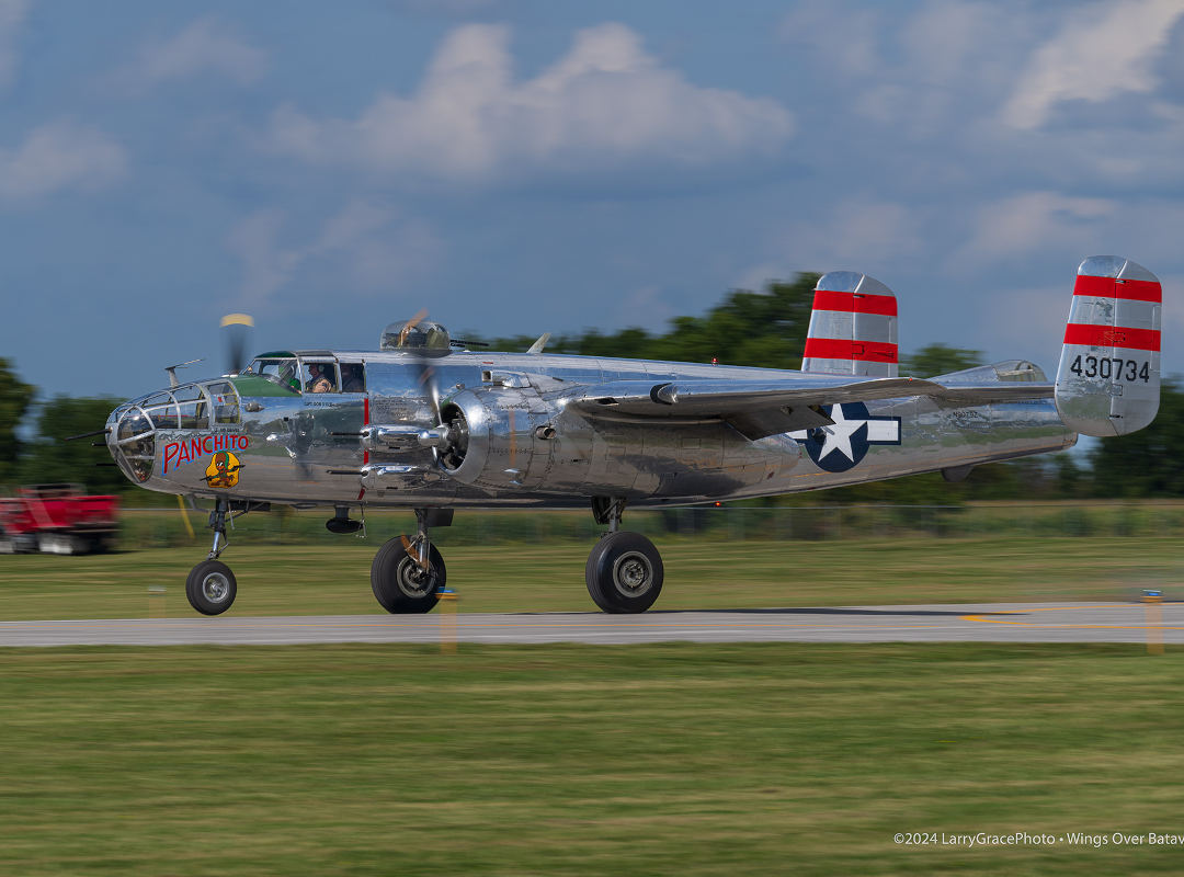 B-25 Mitchell bomber “Panchito” taxis along the runway, displaying its polished silver finish, U.S. military markings, and distinctive red-striped twin tail.