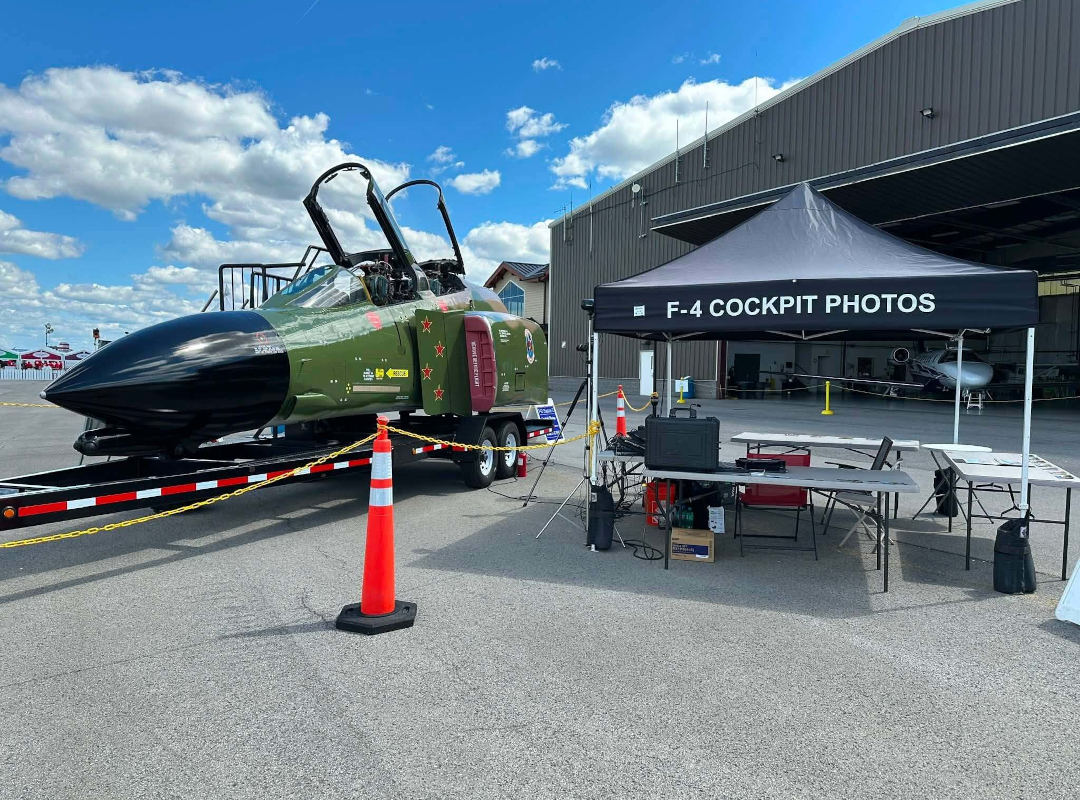F-4 Phantom II cockpit display with open canopies beside a tent offering cockpit photo experiences at the Wings Over Batavia Air Show.